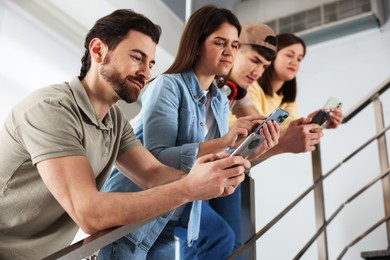 Photo of Internet addiction. Group of people with smartphones on stairs indoors