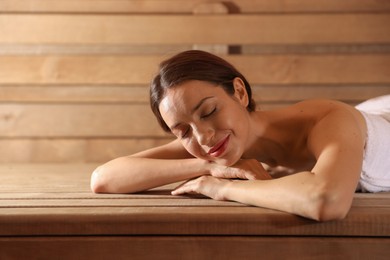 Photo of Beautiful woman relaxing on bench at sauna. Space for text