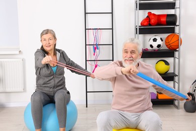 Photo of Elderly couple exercising with elastic bands and fitness balls at home