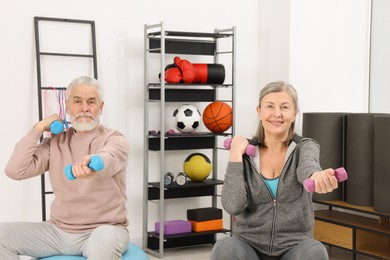 Photo of Elderly couple exercising with dumbbells at home