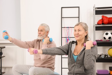 Photo of Elderly couple exercising with dumbbells at home