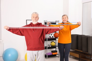 Photo of Elderly couple exercising with fitness elastic bands at home