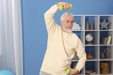 Photo of Elderly man exercising with dumbbells at home