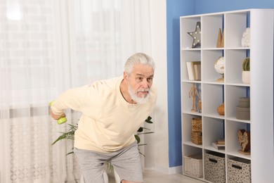 Photo of Elderly man exercising with dumbbells at home