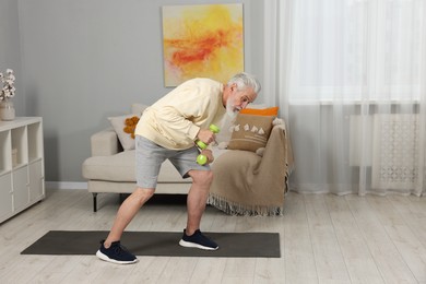 Photo of Elderly man exercising with dumbbells at home