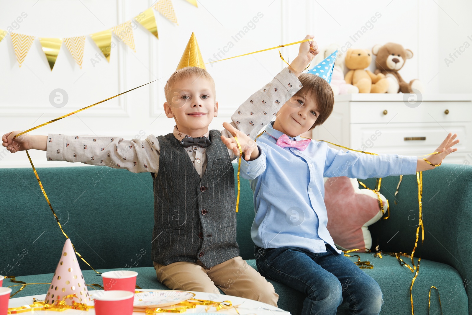 Photo of Children in conical paper hats indoors. Surprise party