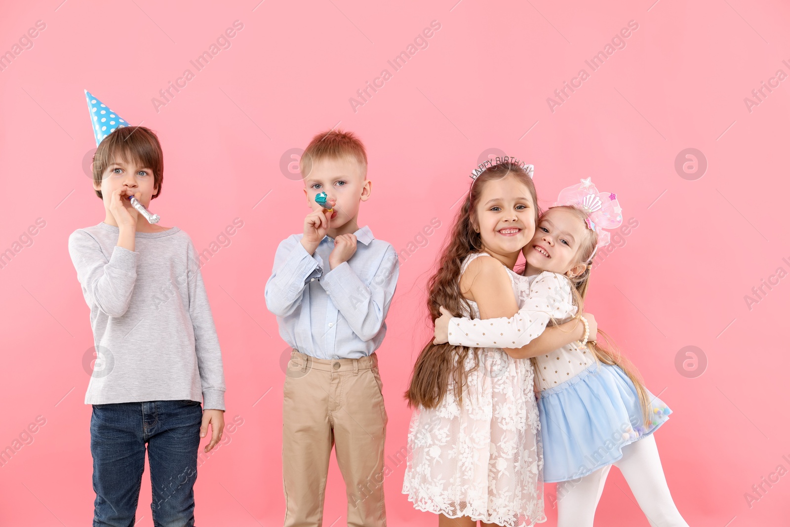 Photo of Children with blowers on pink background. Birthday surprise party