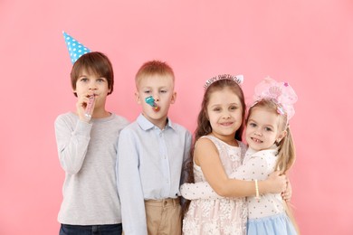 Photo of Children with blowers on pink background. Birthday surprise party