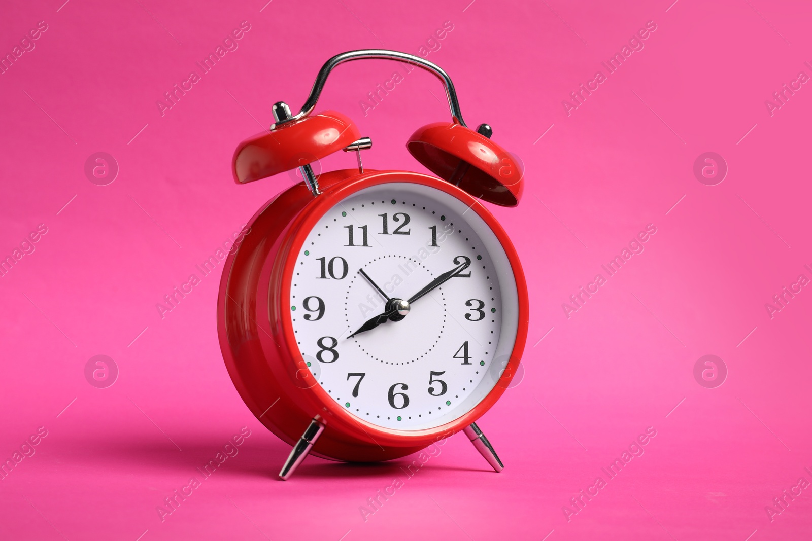 Photo of One red alarm clock on bright pink background