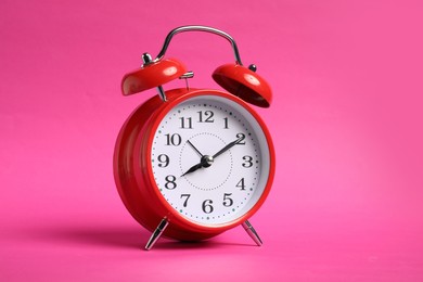 Photo of One red alarm clock on bright pink background