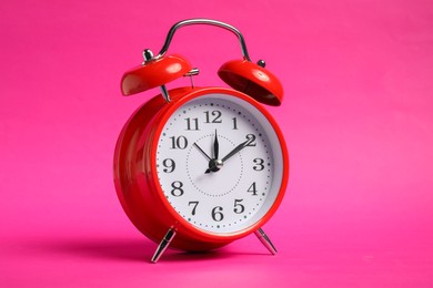 Photo of One red alarm clock on bright pink background