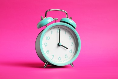 Photo of One turquoise alarm clock on bright pink background