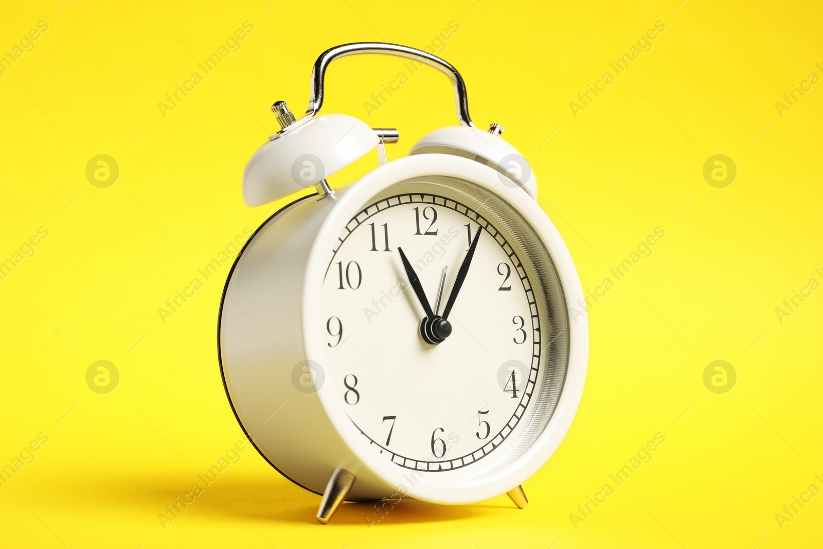 Photo of One white alarm clock on yellow background