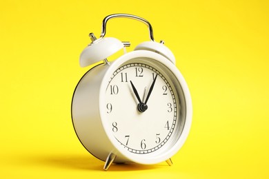 Photo of One white alarm clock on yellow background