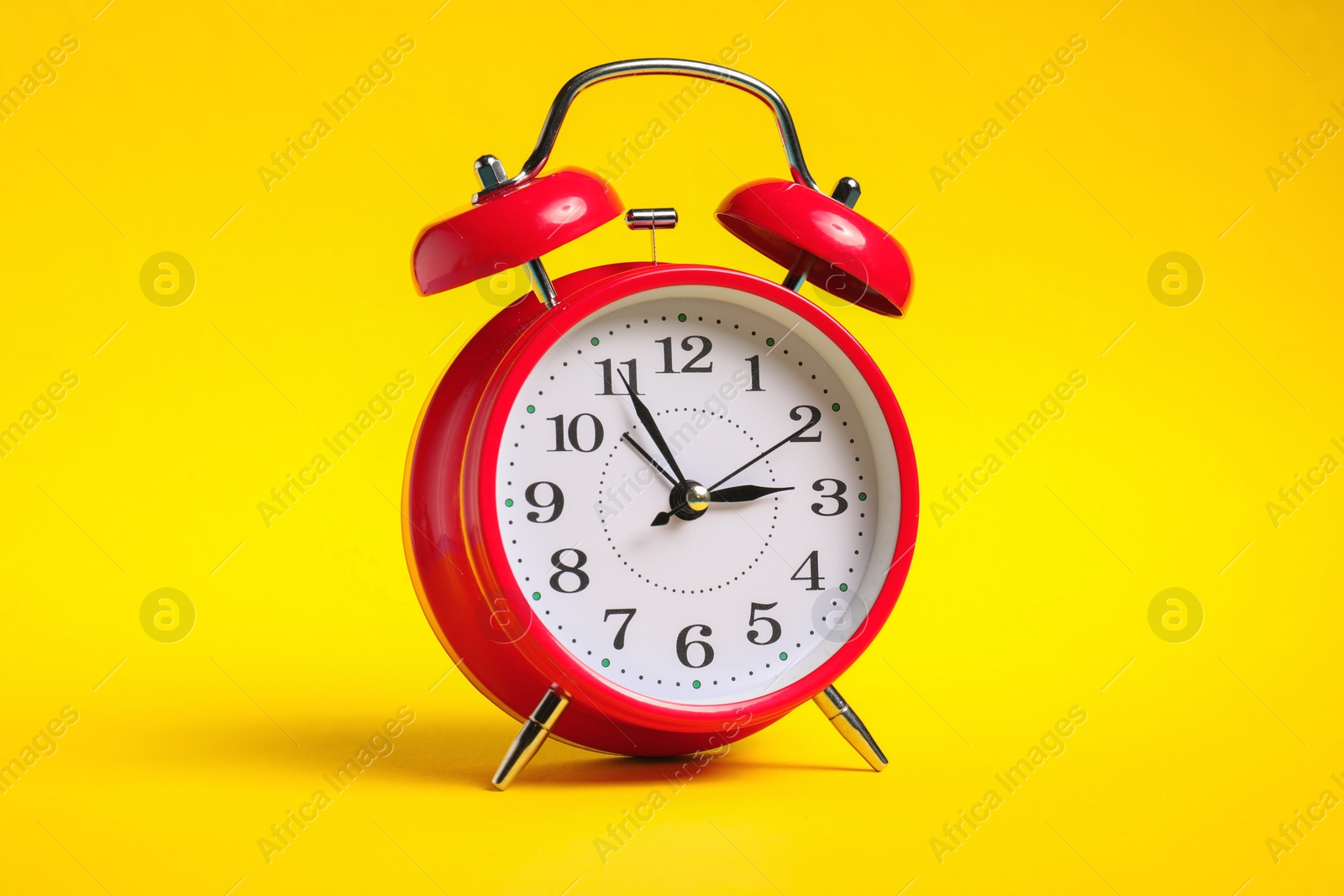 Photo of One red alarm clock on yellow background