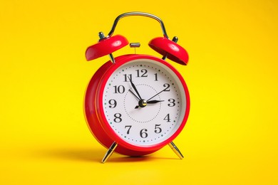 Photo of One red alarm clock on yellow background