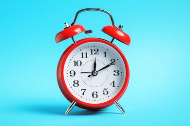 Photo of One red alarm clock on light blue background