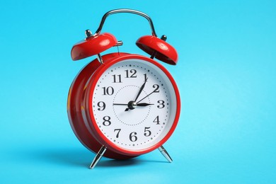 Photo of One red alarm clock on light blue background