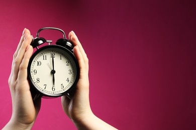 Photo of Woman with black alarm clock on bright pink background, closeup. Space for text