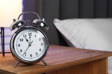 Photo of Alarm clock on wooden nightstand near bed. Space for text