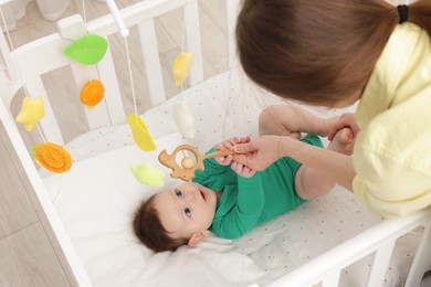 Photo of Mother playing with her cute baby in crib at home