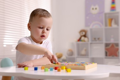 Photo of Motor skills development. Little boy playing with Times table tray indoors