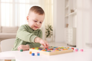 Photo of Motor skills development. Little boy playing with Times table tray indoors