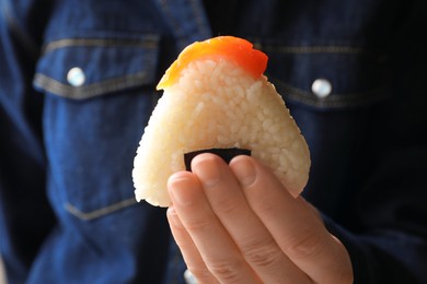 Photo of Woman with tasty onigiri (Japanese rice ball) indoors, closeup