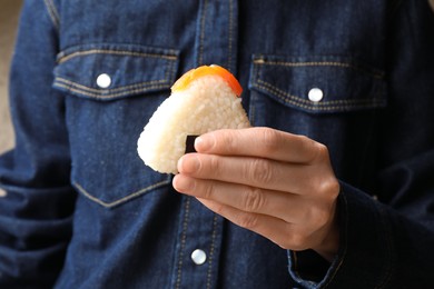 Photo of Woman with tasty onigiri (Japanese rice ball) indoors, closeup