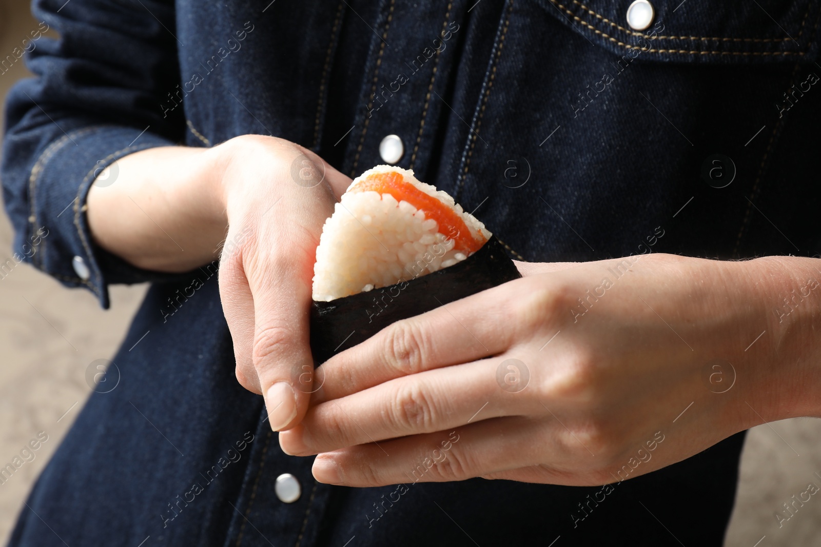 Woman with tasty onigiri (Japanese rice ball) indoors, closeup Photo of Woman with tasty onigiri (Japanese rice ball) indoors, closeup
