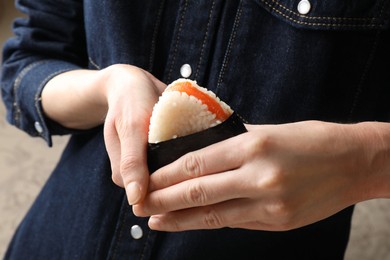 Photo of Woman with tasty onigiri (Japanese rice ball) indoors, closeup