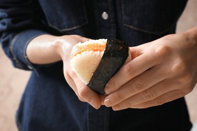 Photo of Woman with tasty onigiri (Japanese rice ball) indoors, closeup