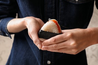 Photo of Woman with tasty onigiri (Japanese rice ball) indoors, closeup