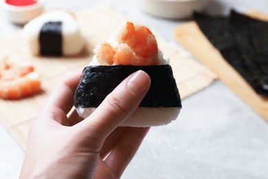 Photo of Woman with tasty onigiri (Japanese rice ball) at light table, closeup