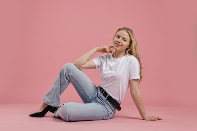 Photo of Smiling woman in stylish jeans on pink background