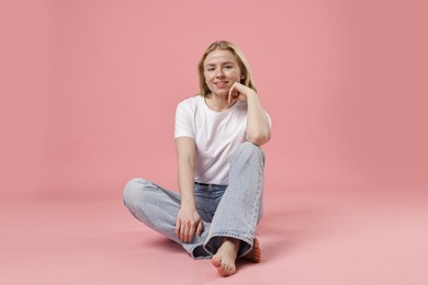 Photo of Smiling woman in stylish jeans on pink background