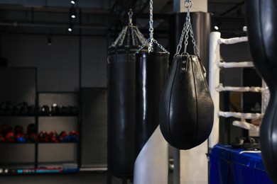 Photo of Punching bags near boxing ring indoors. Space for text