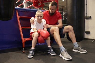 Photo of Coach comforting sad boy near boxing ring