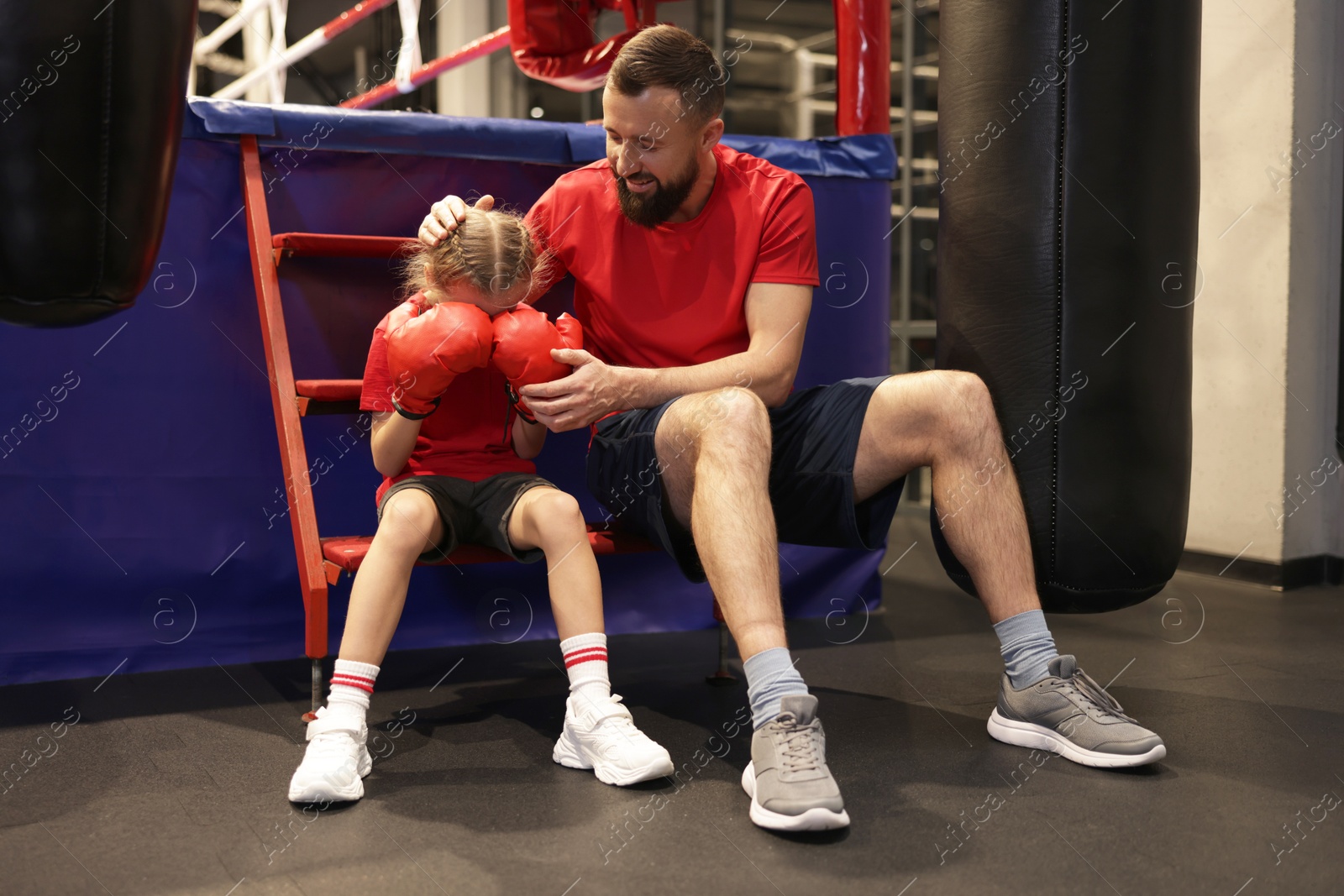 Photo of Coach comforting sad girl near boxing ring