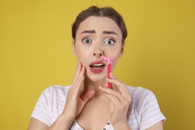 Photo of Emotional woman shaving her mustache with razor on light green background