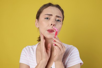 Photo of Beautiful woman shaving her mustache with razor on light green background