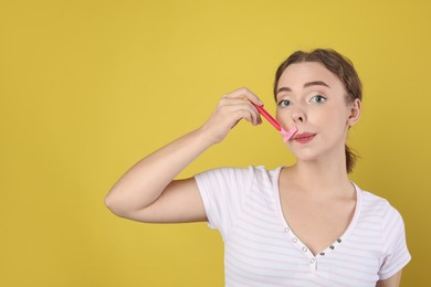 Photo of Beautiful woman shaving her mustache with razor on light green background. Space for text