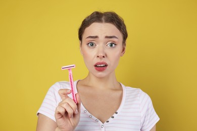 Photo of Beautiful woman with razor on light green background. Hair removal tool