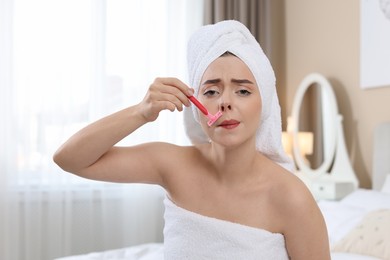 Photo of Beautiful woman shaving her mustache with razor at home