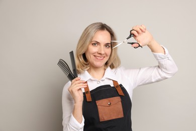 Photo of Smiling hairdresser with combs and brush on gray background