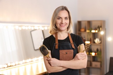 Photo of Hairdresser with brush, comb and scissors in beauty salon