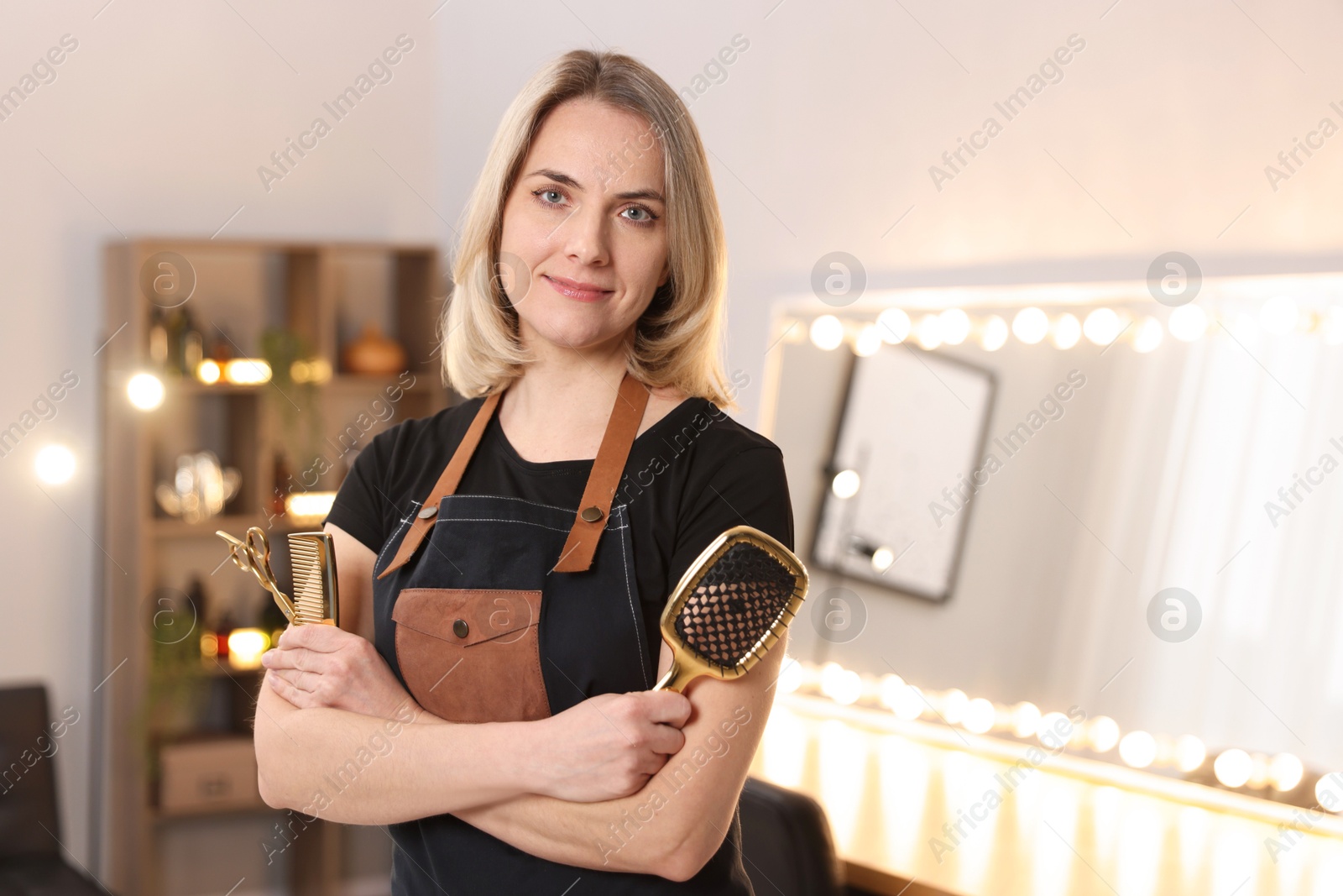 Photo of Hairdresser with brush, comb and scissors in beauty salon