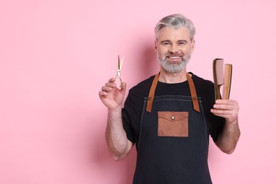 Photo of Smiling hairdresser with scissors and combs on pink background, space for text