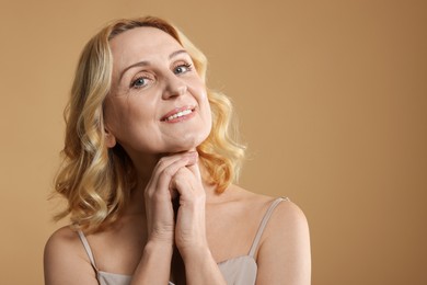 Photo of Portrait of smiling middle aged woman on beige background. Space for text