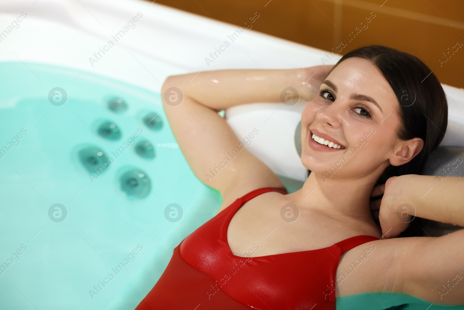 Photo of Beautiful woman relaxing in hot tub indoors